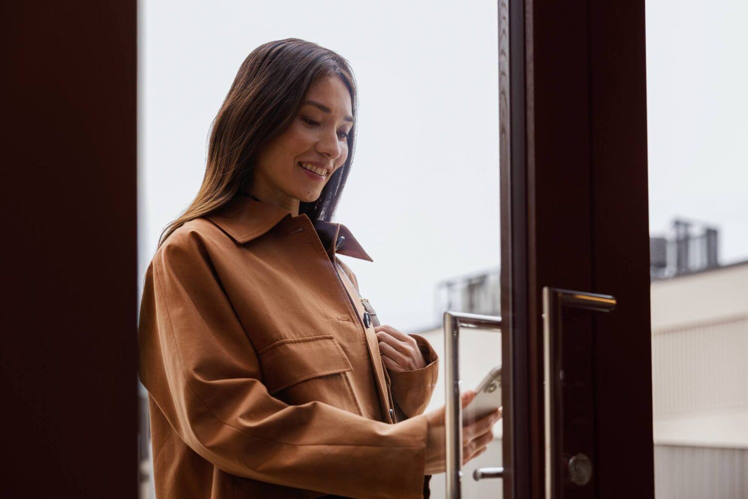 A person using a phone for smart access at a commercial door